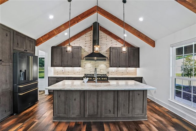 kitchen featuring light stone counters, high quality fridge, an island with sink, and dark brown cabinetry