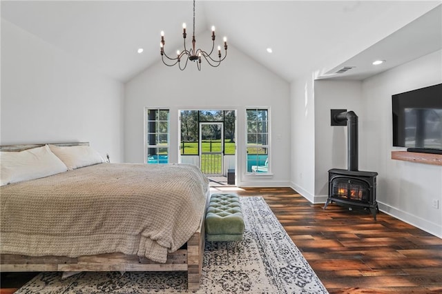 bedroom featuring dark wood-type flooring, a chandelier, high vaulted ceiling, a wood stove, and access to exterior