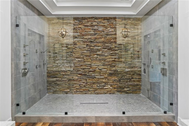 bathroom with tiled shower and a tray ceiling