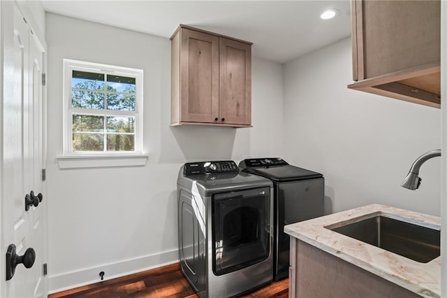 washroom with sink, dark hardwood / wood-style floors, cabinets, and washing machine and clothes dryer