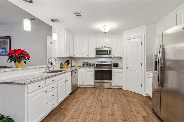 kitchen with sink, kitchen peninsula, hanging light fixtures, white cabinetry, and stainless steel appliances