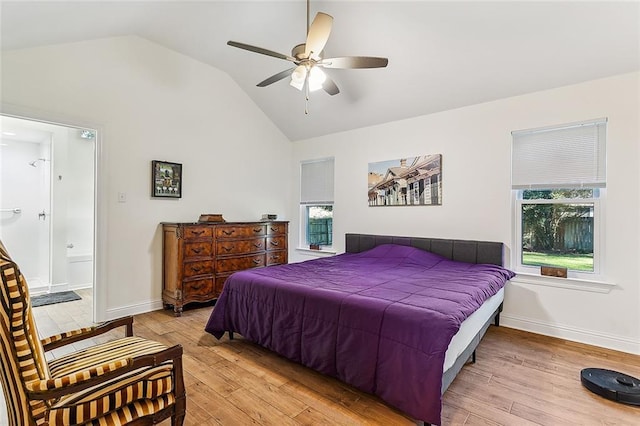 bedroom featuring ceiling fan, light wood-type flooring, ensuite bathroom, and vaulted ceiling