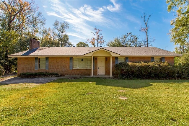 ranch-style home featuring brick siding, a chimney, and a front lawn