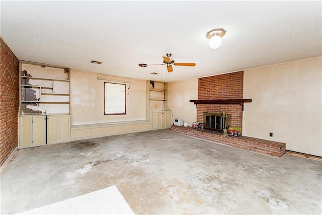 unfurnished living room featuring unfinished concrete flooring, a textured ceiling, brick wall, a brick fireplace, and ceiling fan