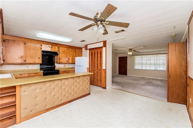 kitchen with visible vents, freestanding refrigerator, light countertops, black range with electric cooktop, and exhaust hood