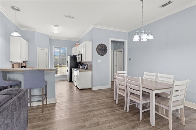 dining area featuring crown molding, dark hardwood / wood-style floors, and a notable chandelier