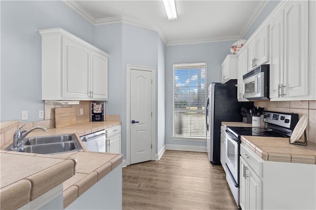 kitchen with tile countertops, white cabinetry, sink, and stainless steel appliances