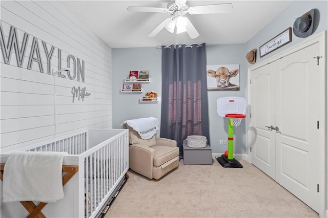 carpeted bedroom featuring ceiling fan and a crib