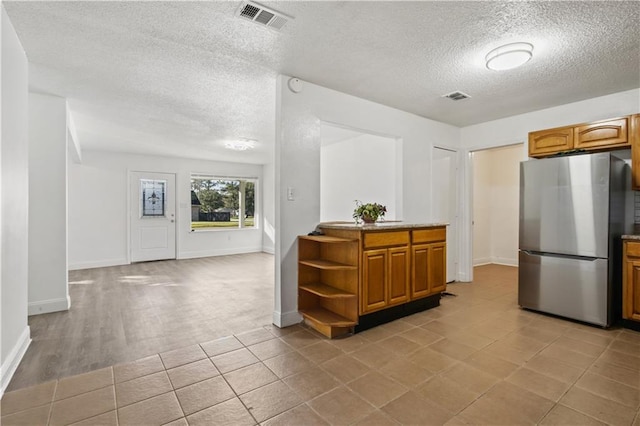 1492 W Hall Ave, Slidell, LA 70460 - kitchen with freestanding refrigerator, brown cabinetry, a textured ceiling, open shelves, and baseboards