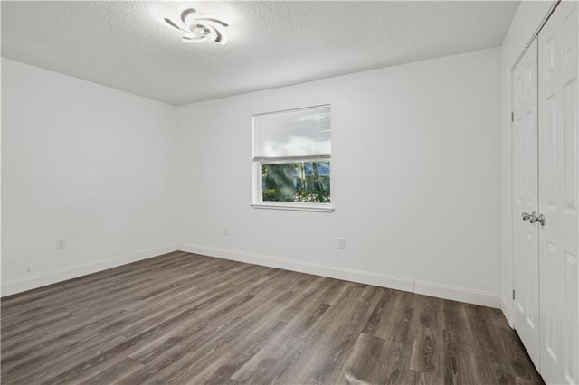 spare room featuring dark hardwood / wood-style flooring and a textured ceiling