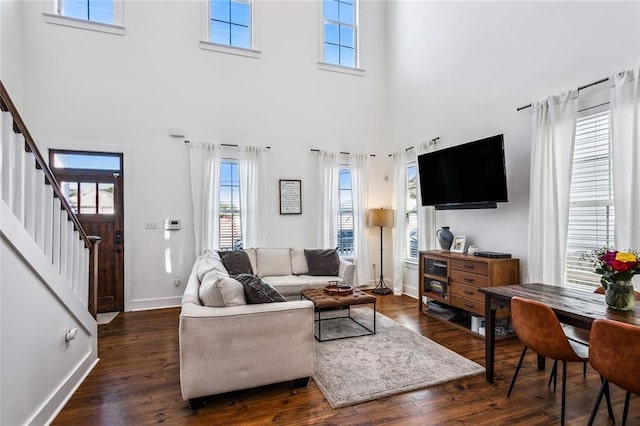 living room with a towering ceiling, dark hardwood / wood-style floors, and plenty of natural light