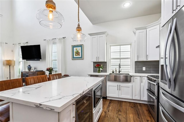 kitchen featuring a kitchen bar, white cabinetry, sink, and appliances with stainless steel finishes