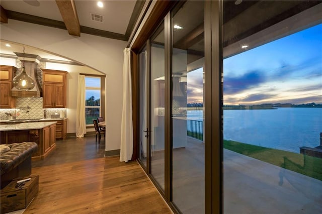 interior space with beam ceiling, crown molding, a water view, and dark hardwood / wood-style flooring