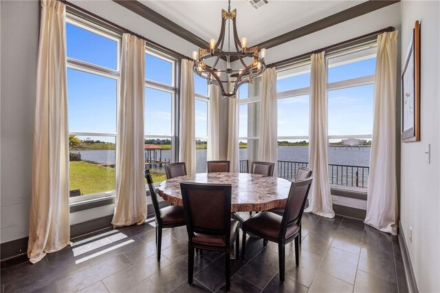 dining area with plenty of natural light, a notable chandelier, ornamental molding, and a water view