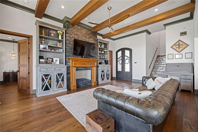 living room featuring ceiling fan, built in features, dark hardwood / wood-style flooring, and beamed ceiling