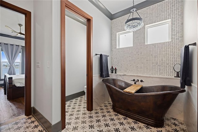 bathroom featuring a tub, toilet, and a chandelier