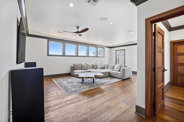 living room featuring wood-type flooring, ornamental molding, and ceiling fan