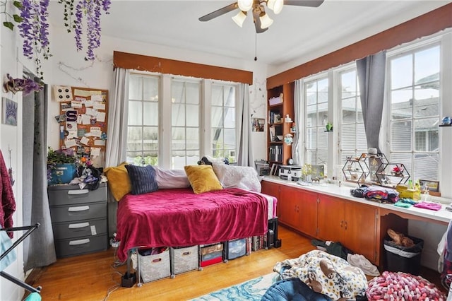 bedroom with multiple windows, ceiling fan, and light wood-type flooring