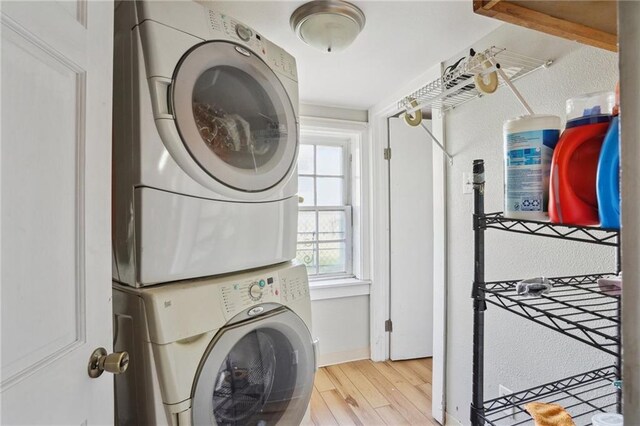 washroom featuring stacked washer and dryer and light hardwood / wood-style floors