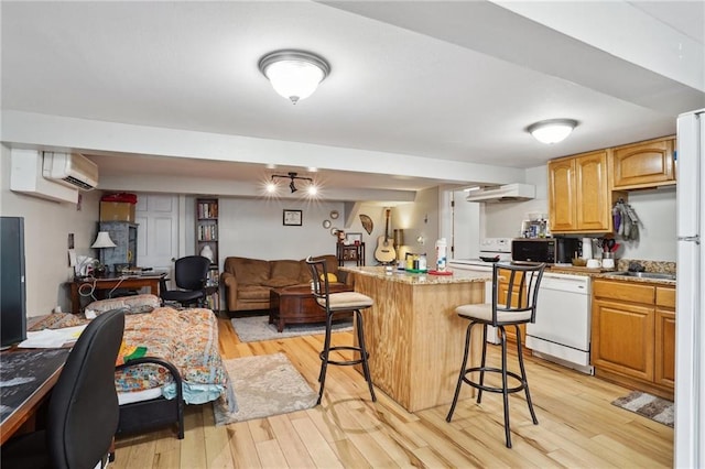 kitchen with dishwasher, a center island, a wall mounted air conditioner, a breakfast bar area, and light wood-type flooring