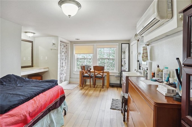 bedroom featuring an AC wall unit, sink, and light wood-type flooring