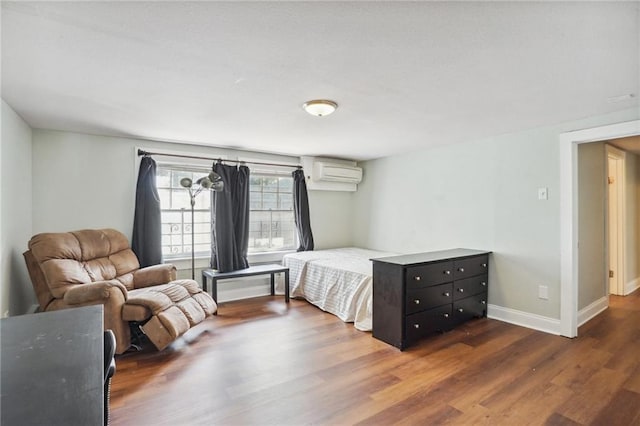 bedroom with dark hardwood / wood-style flooring and a wall unit AC