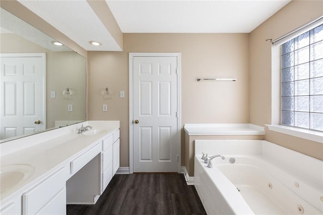 bathroom with hardwood / wood-style flooring, a relaxing tiled tub, and vanity