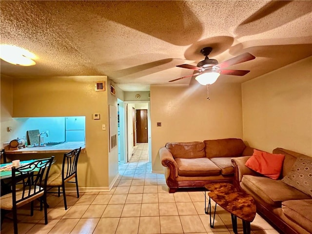 tiled living room featuring a textured ceiling, ceiling fan, and sink