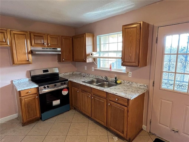 kitchen featuring a healthy amount of sunlight, light tile patterned floors, sink, and stainless steel stove