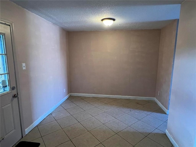 tiled empty room featuring a textured ceiling