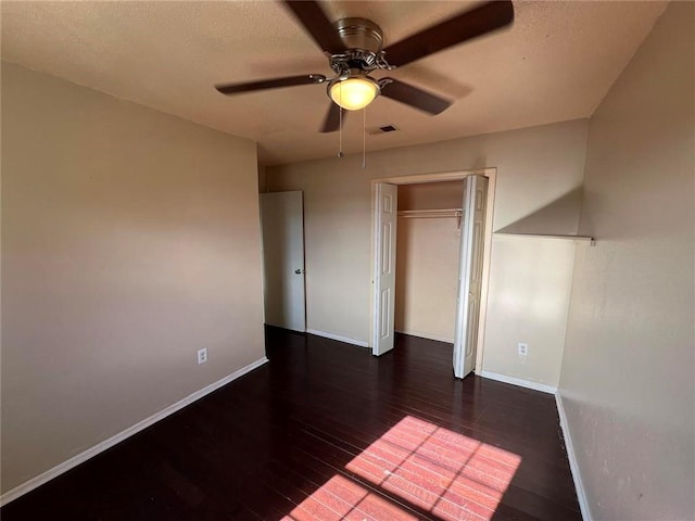 unfurnished bedroom with ceiling fan, dark hardwood / wood-style flooring, and a closet