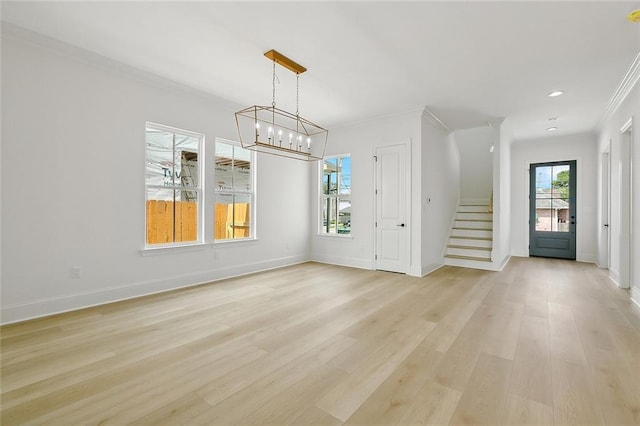 foyer entrance with light hardwood / wood-style floors, crown molding, a wealth of natural light, and a chandelier