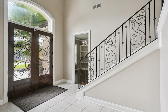 tiled foyer featuring an inviting chandelier, crown molding, and french doors