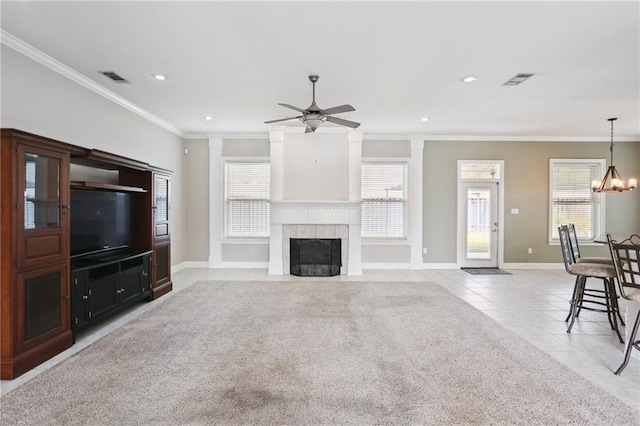 tiled living room featuring a fireplace, ceiling fan with notable chandelier, crown molding, and a healthy amount of sunlight