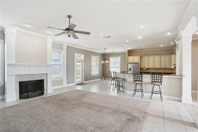 kitchen with ornamental molding, stainless steel refrigerator with ice dispenser, a breakfast bar area, and a tiled fireplace