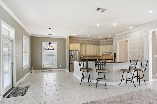 kitchen featuring stainless steel refrigerator with ice dispenser, ornamental molding, a breakfast bar, hanging light fixtures, and light tile patterned flooring