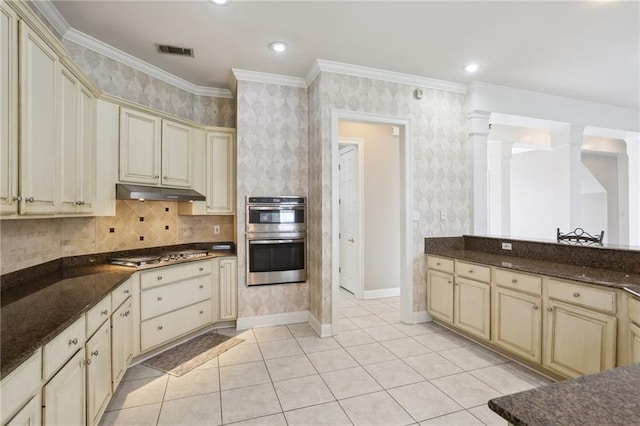 kitchen featuring dark stone counters, stainless steel appliances, and cream cabinetry