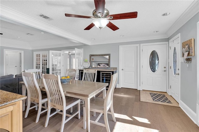 dining area featuring ceiling fan, crown molding, light wood-type flooring, and a textured ceiling