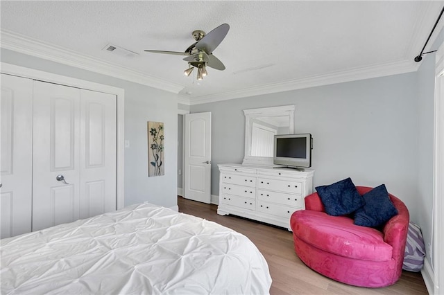 bedroom featuring ceiling fan, dark hardwood / wood-style flooring, crown molding, and a closet