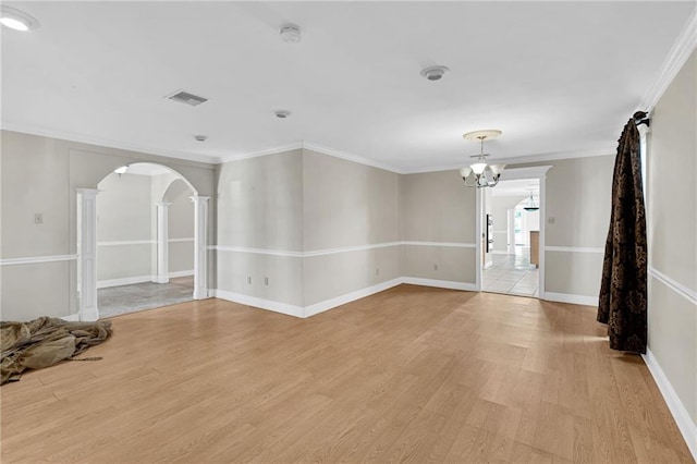 empty room featuring an inviting chandelier, ornamental molding, and light hardwood / wood-style flooring