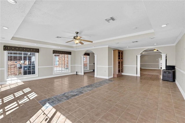 unfurnished living room with a raised ceiling, ornate columns, ceiling fan, and ornamental molding