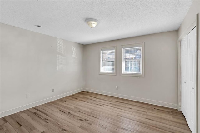 unfurnished bedroom featuring a closet, a textured ceiling, and light wood-type flooring