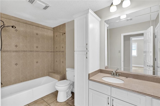 full bathroom featuring vanity, tile patterned floors, tiled shower / bath, toilet, and a textured ceiling