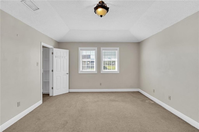 carpeted spare room featuring a textured ceiling and vaulted ceiling