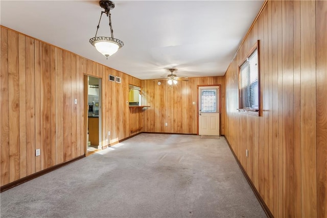 spare room with carpet, ceiling fan, and wooden walls