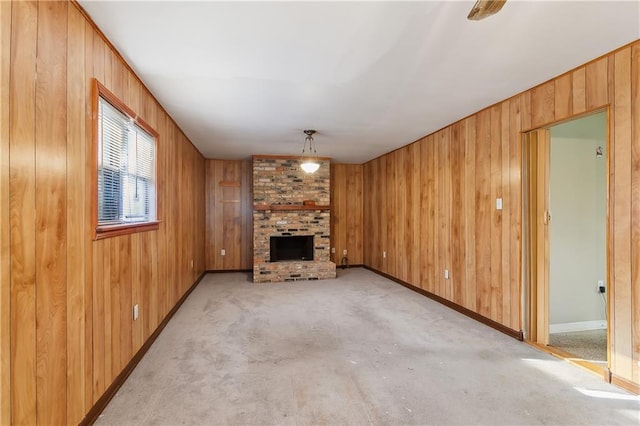 unfurnished living room featuring wooden walls, light colored carpet, and a brick fireplace