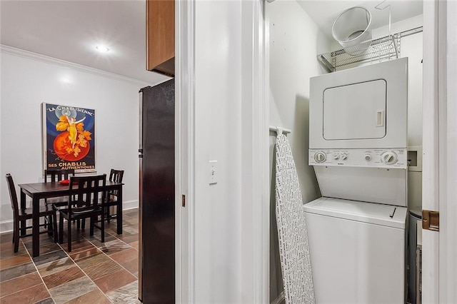 clothes washing area with ornamental molding and stacked washer and clothes dryer