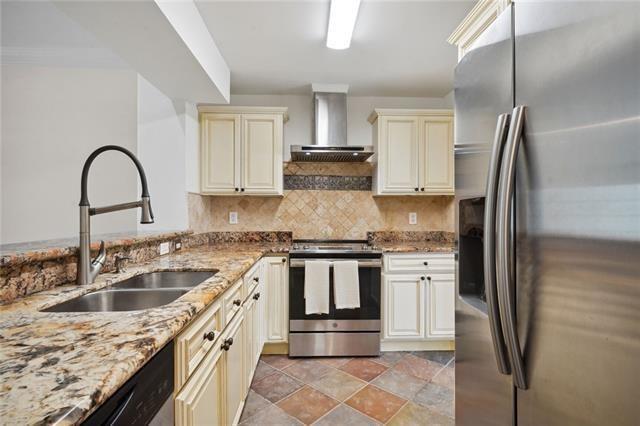 kitchen featuring cream cabinetry, wall chimney exhaust hood, sink, and stainless steel appliances