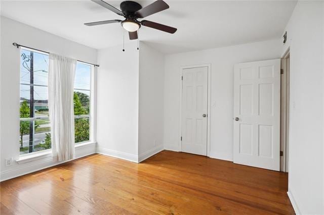 unfurnished bedroom with multiple windows, ceiling fan, and wood-type flooring