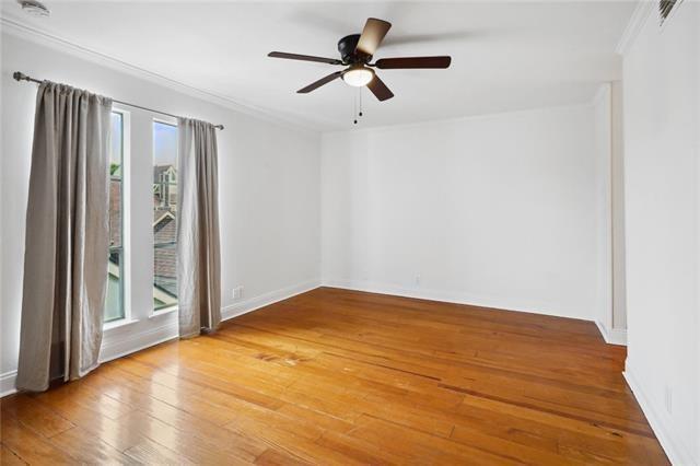 empty room featuring wood-type flooring, a wealth of natural light, ornamental molding, and ceiling fan